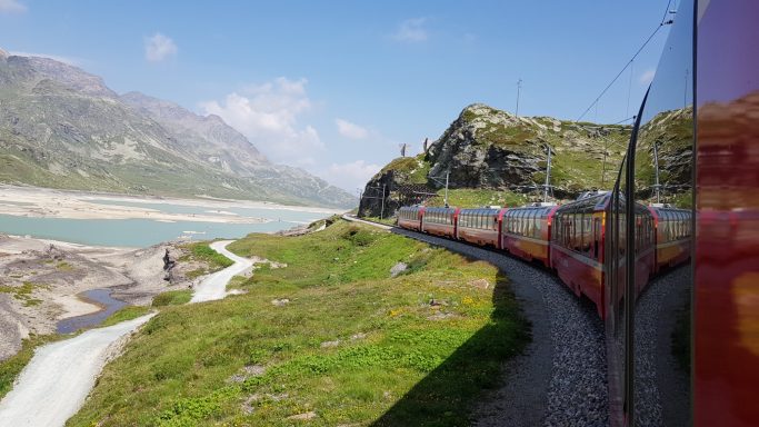 Blick aus dem Fenster des Bernina-Express, der gerade an einem See vorbeifährt