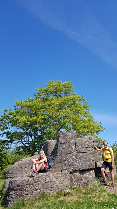 Zwei Wanderer sitzen bzw. stehen an den Ketzersteinen, einer Felsformation aus Basalt